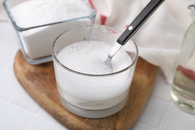 Chemical reaction of vinegar and baking soda in glass bowl on white table, closeup