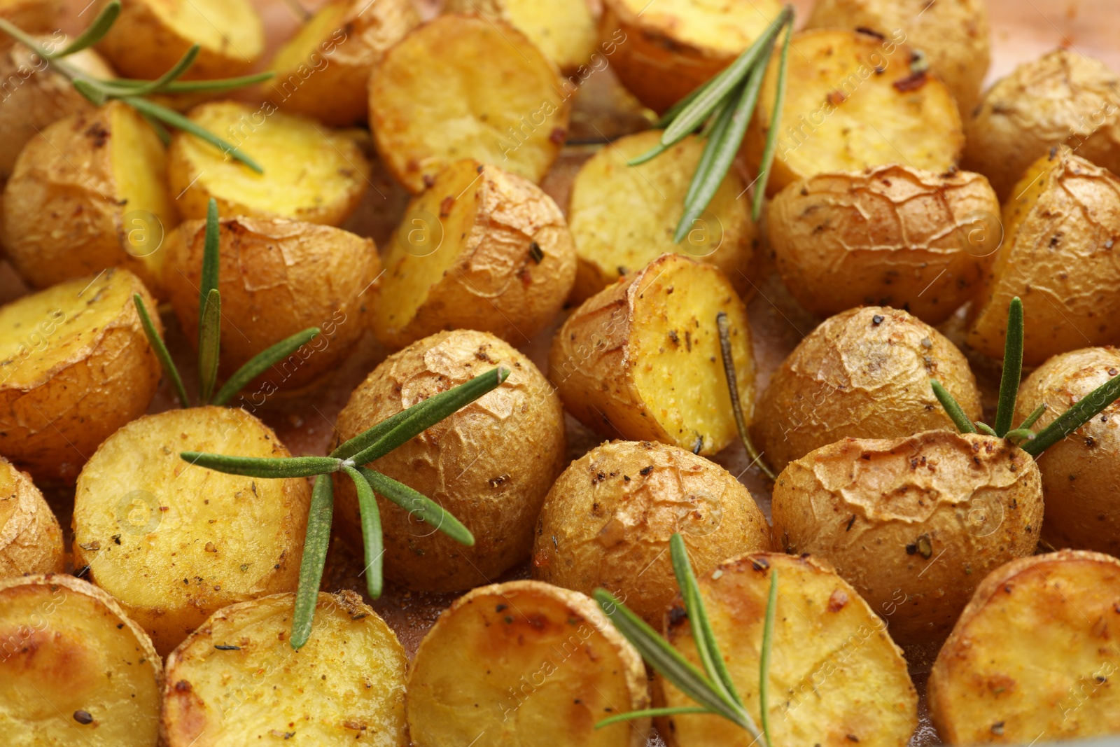 Photo of Delicious baked potatoes with rosemary as background, closeup