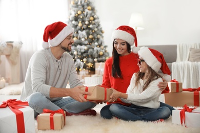 Photo of Happy family with Christmas gifts on floor at home