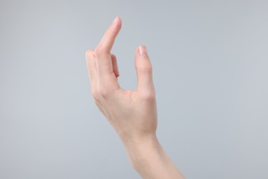 Photo of Woman holding something in fingers on grey background, closeup