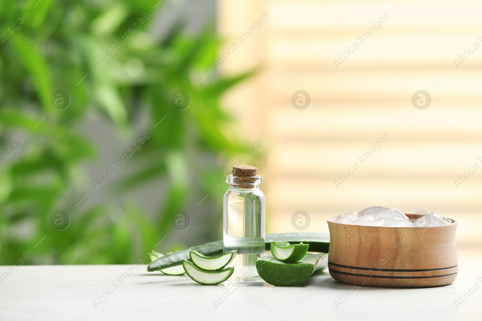 Photo of Bowl with aloe vera gel and bottle of juice on table against blurred background