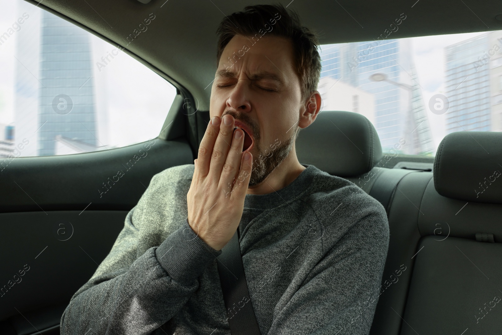 Photo of Sleepy tired man yawning in his modern car