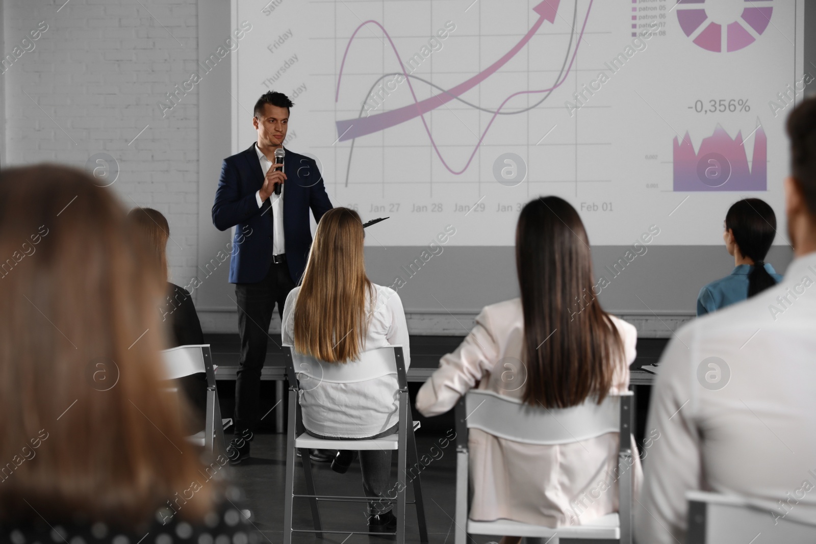 Photo of Male business trainer giving lecture in conference room with projection screen