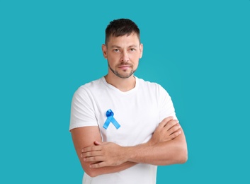 Photo of Man with blue ribbon on turquoise background. Urology cancer awareness