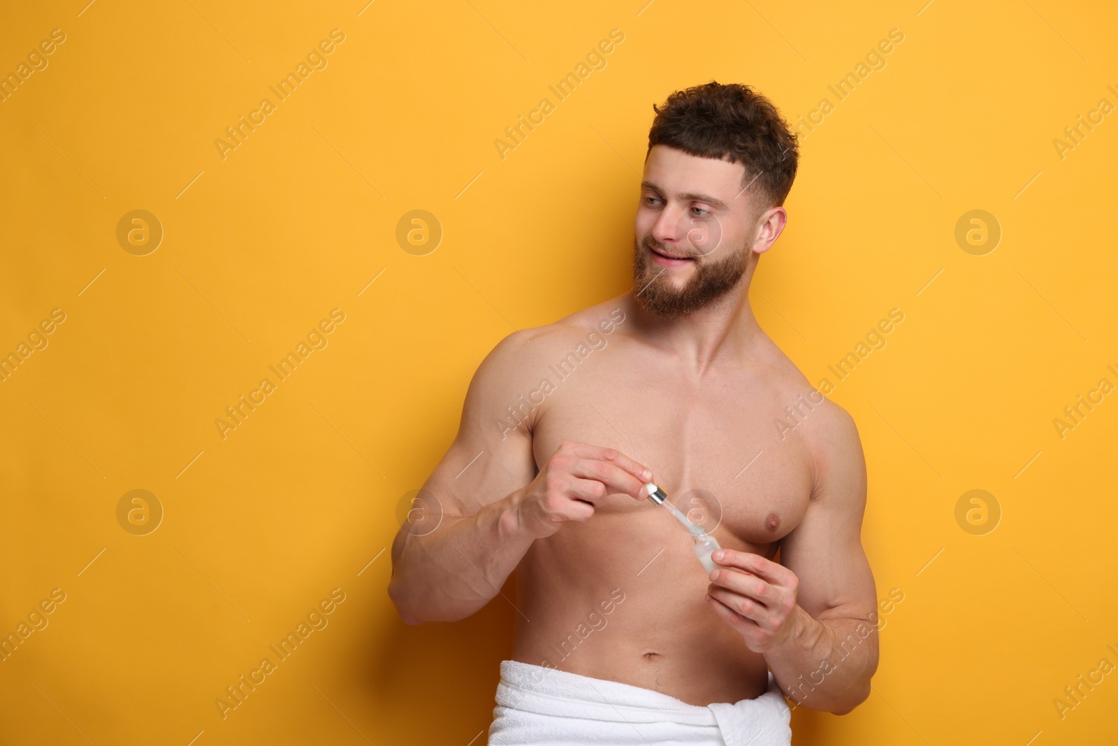 Photo of Handsome man with serum on orange background, space for text