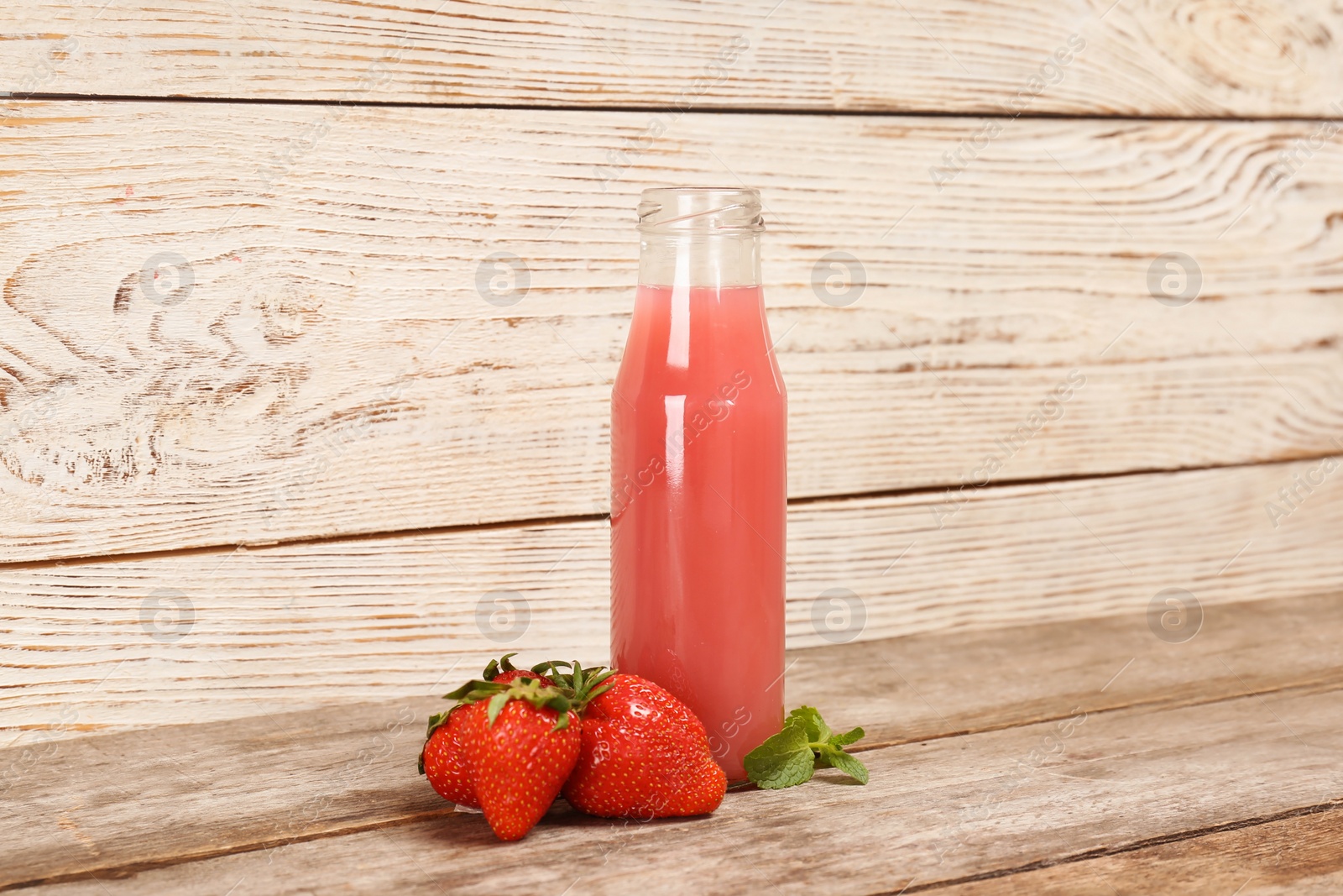 Photo of Bottle with tasty strawberry juice on table