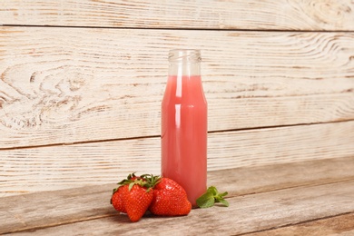 Bottle with tasty strawberry juice on table