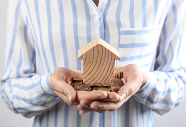 Photo of Woman holding coins and house model, closeup