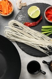 Photo of Flat lay composition with black wok, spices and products on grey textured table