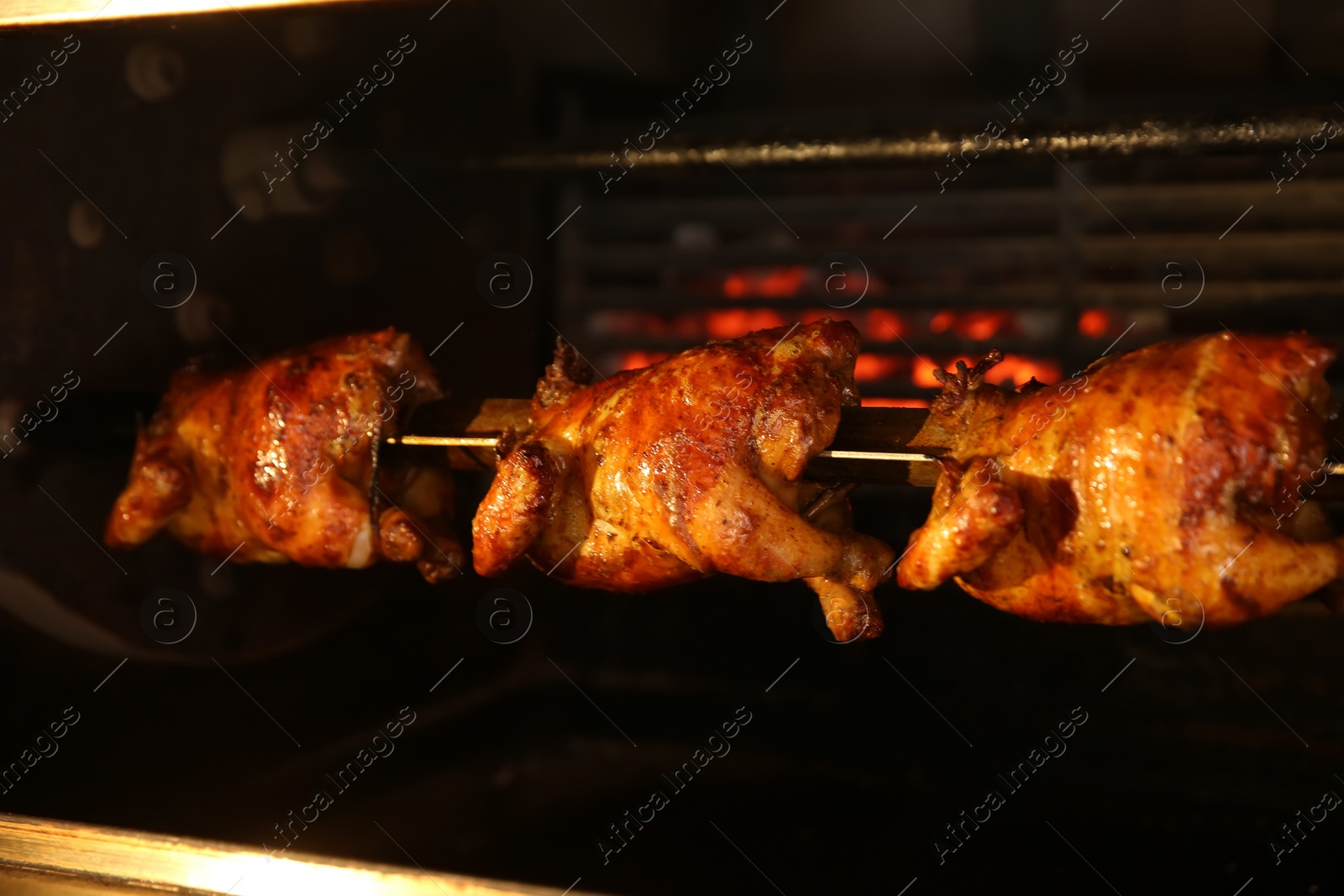 Photo of Grilling whole chickens in rotisserie machine, closeup