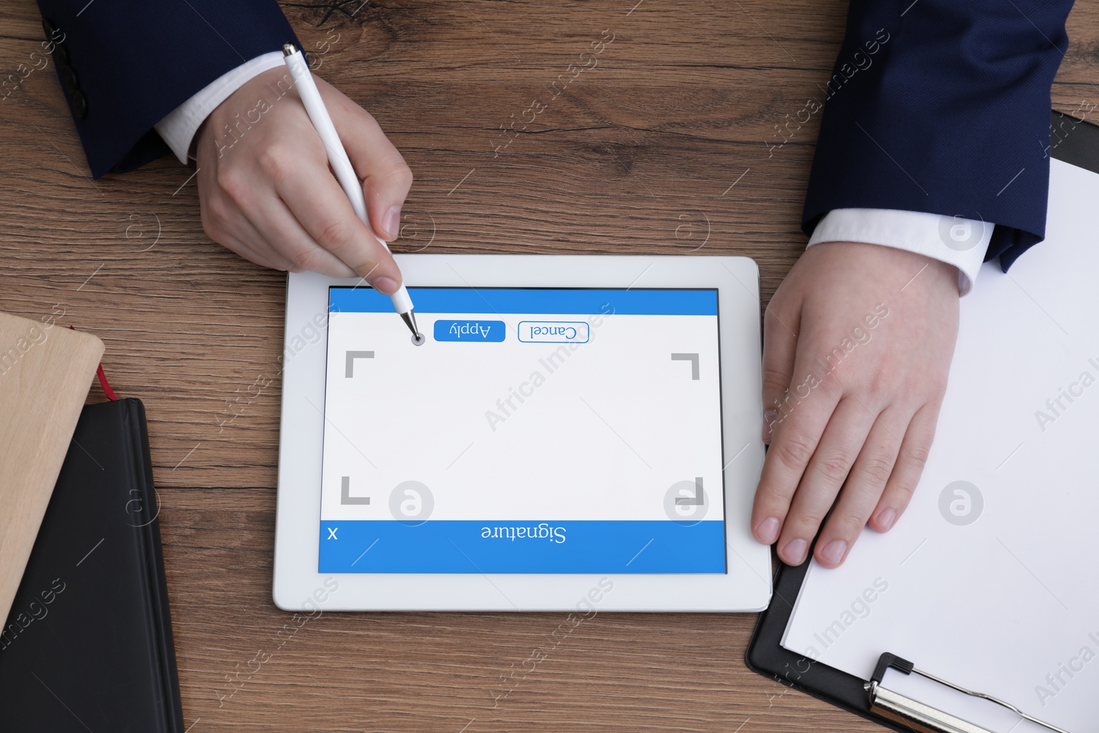 Image of Electronic signature. Man using stylus and tablet at wooden table, top view