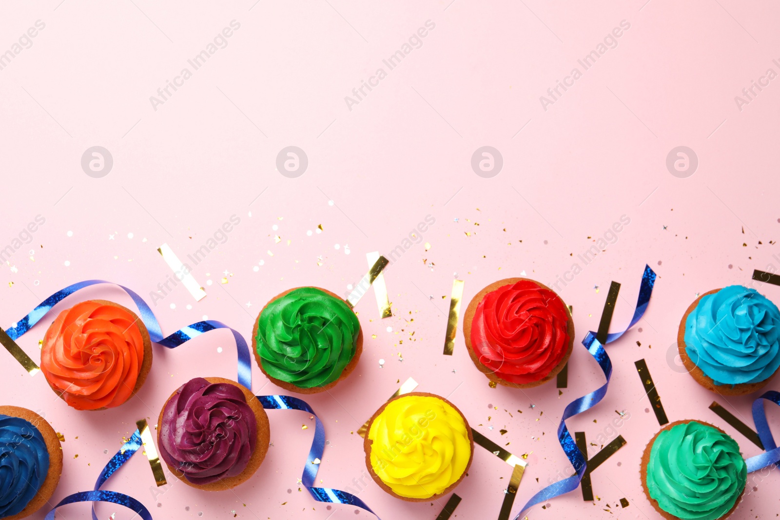 Photo of Flat lay composition with delicious colorful cupcakes and confetti on pink background. Space for text