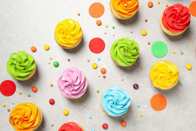 Photo of Colorful birthday cupcakes on light grey table, flat lay
