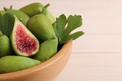 Cut and whole fresh green figs on white wooden table, closeup. Space for text