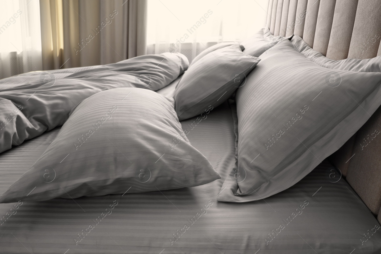 Photo of Comfortable bed with soft blanket and pillows indoors, closeup