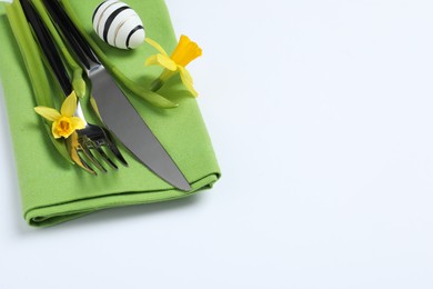 Photo of Cutlery set, Easter egg and narcissuses on white background, space for text. Festive table setting