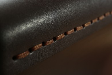 Photo of Dark leather with brown seam as background, closeup