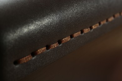 Dark leather with brown seam as background, closeup