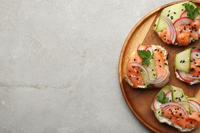 Photo of Tasty canapes with salmon served on light grey table, top view. Space for text
