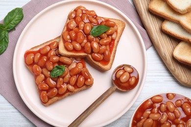 Photo of Toasts with delicious canned beans on white wooden table, flat lay