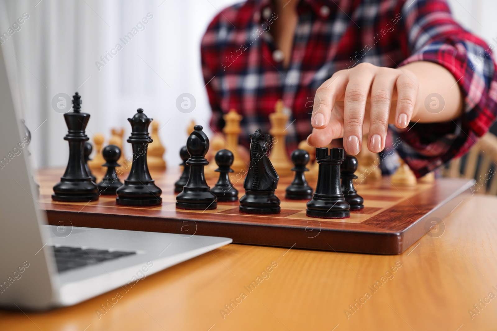 Photo of Woman playing chess with partner through online video chat at table indoors, closeup