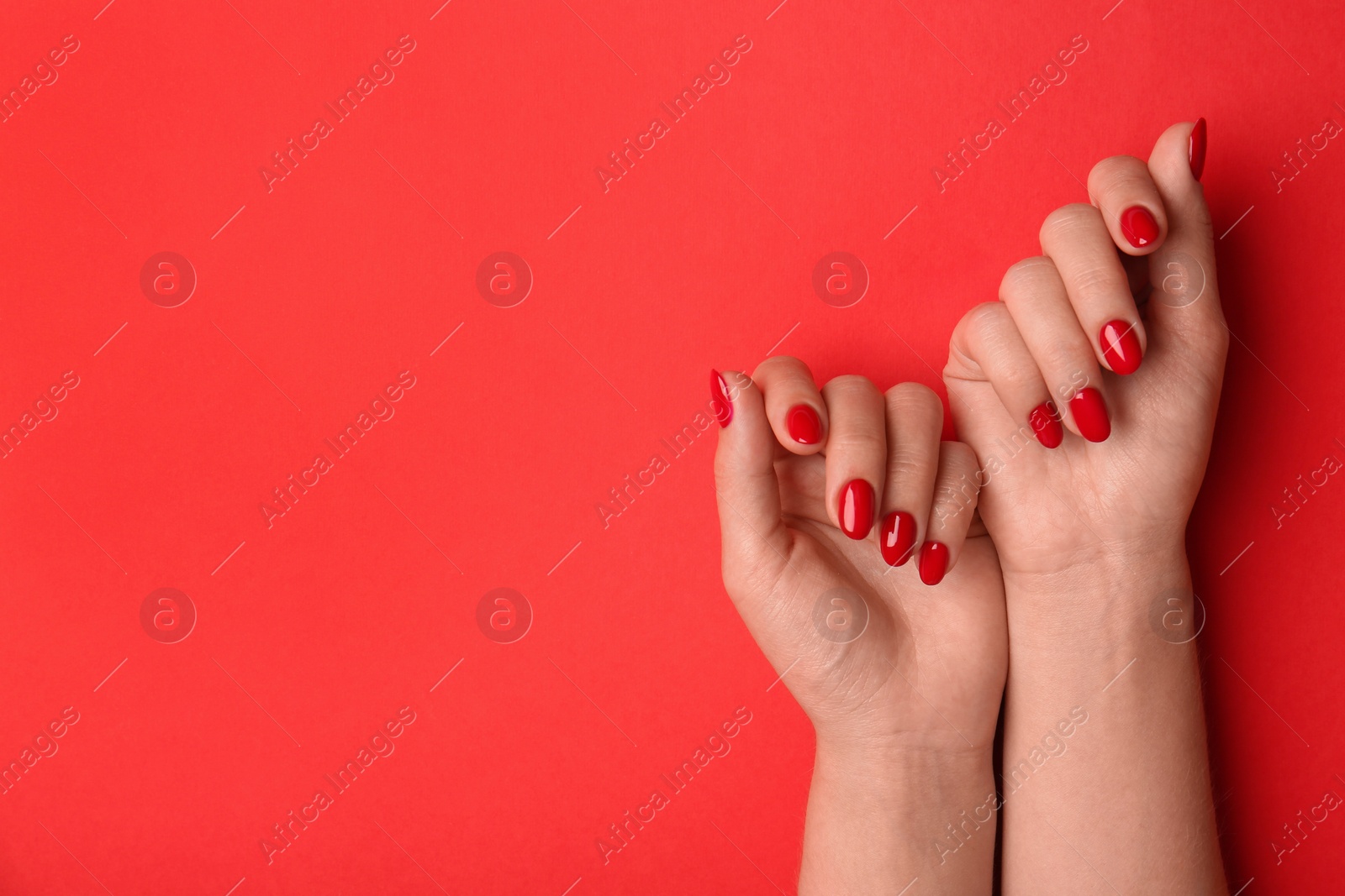 Photo of Woman with gel polish on nails against red background, closeup. Space for text