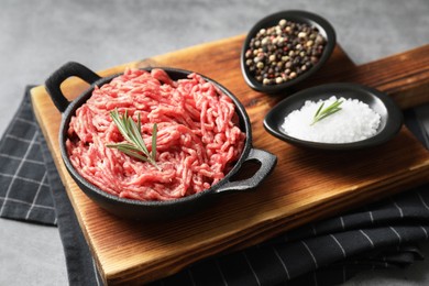 Photo of Raw ground meat in bowl and spices on grey table