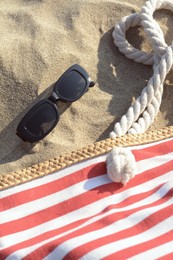 Photo of Stylish sunglasses and beach bag on sand, above view