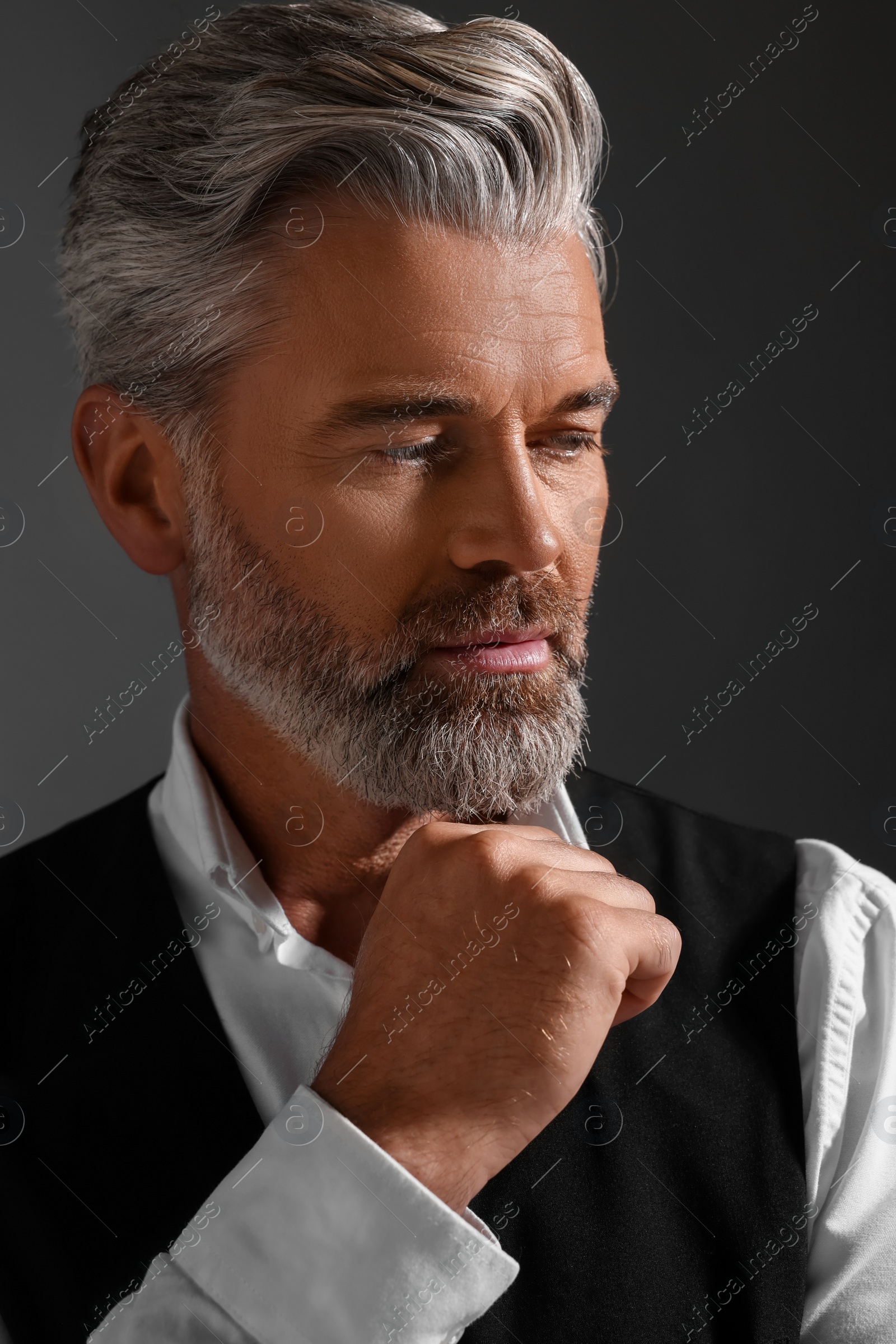 Photo of Portrait of confident man with beautiful hairstyle on dark background