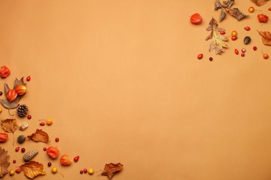 Photo of Dry autumn leaves, berries and cones on light brown background, flat lay. Space for text