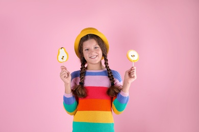 Little girl with candies on color background