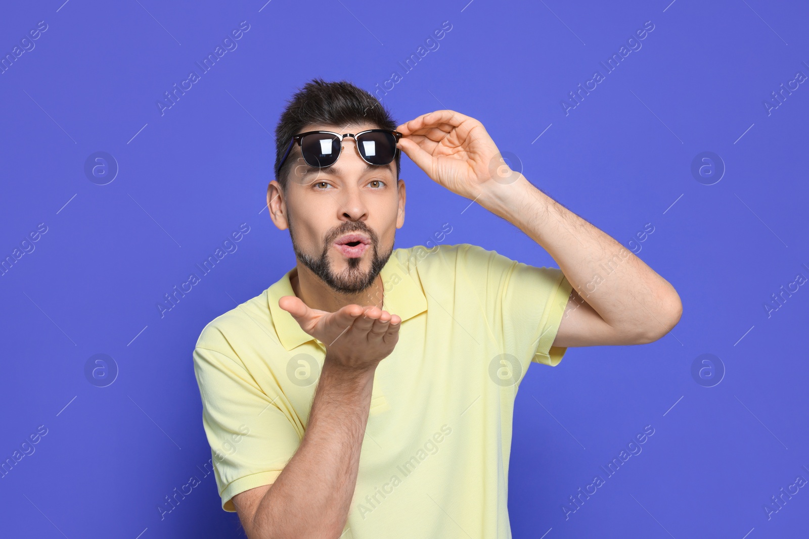 Photo of Handsome man blowing kiss on violet background