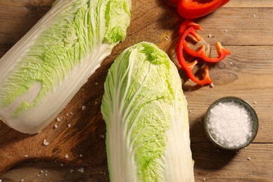 Fresh Chinese cabbages, bell pepper and salt on wooden table, flat lay