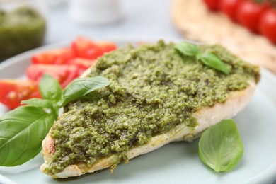 Photo of Delicious chicken breast with pesto sauce and basil on table, closeup