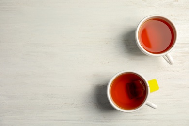 Photo of Cups of delicious tea on wooden background, top view