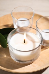 Photo of Wooden plate with burning small candles on table, closeup