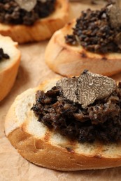 Photo of Delicious bruschettas with truffle sauce on parchment paper, closeup