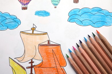 Photo of Coloring page with children drawing and set of pencils, closeup