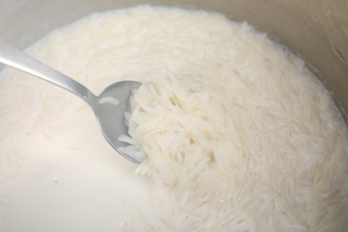 Photo of Cooking tasty rice with milk in pot, closeup