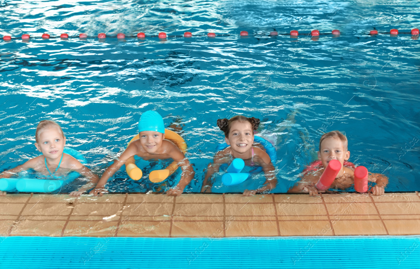 Photo of Little kids with swimming noodles in indoor pool