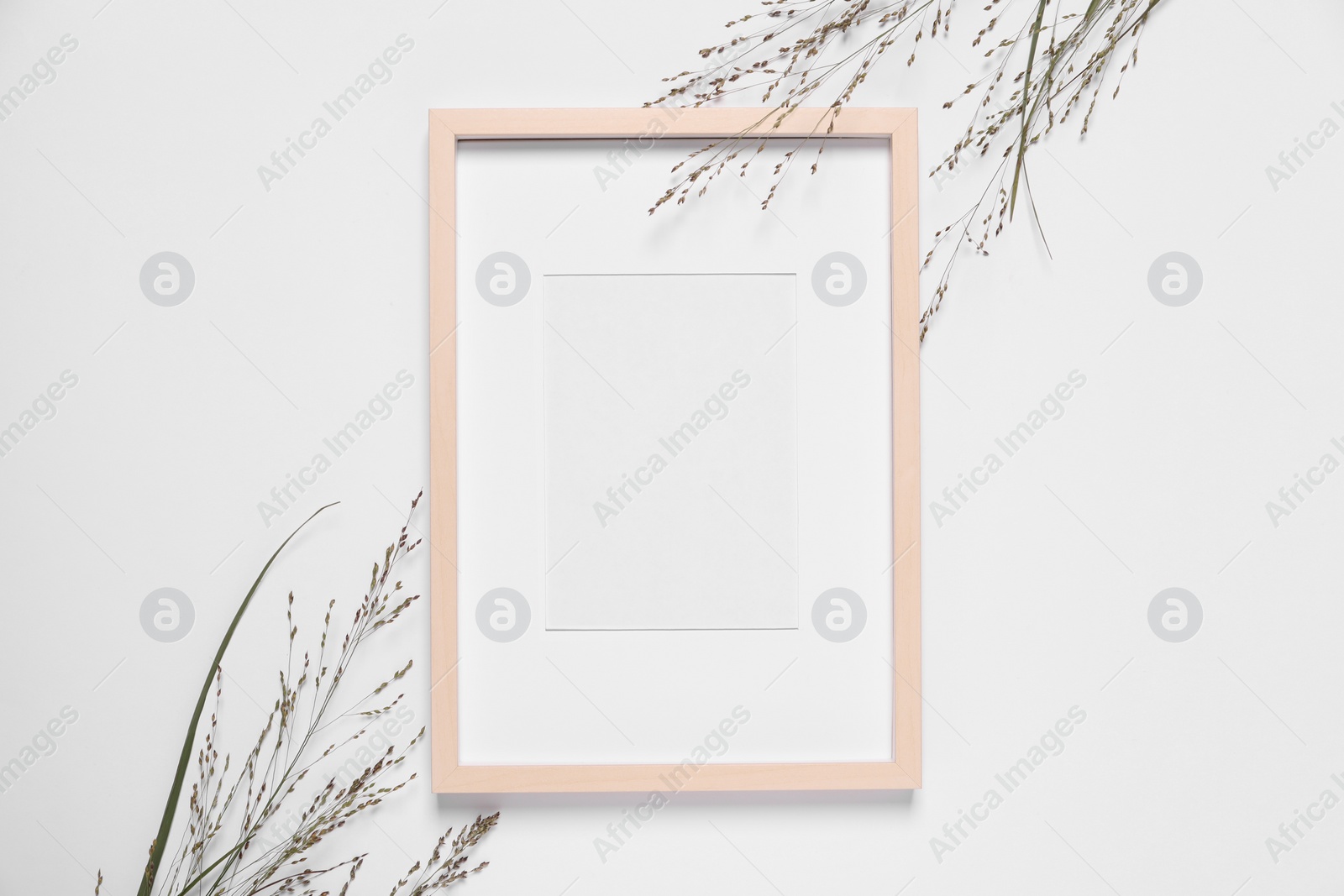 Photo of Empty photo frame and wild flowers on white background, top view. Space for design