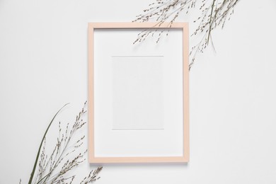 Photo of Empty photo frame and wild flowers on white background, top view. Space for design