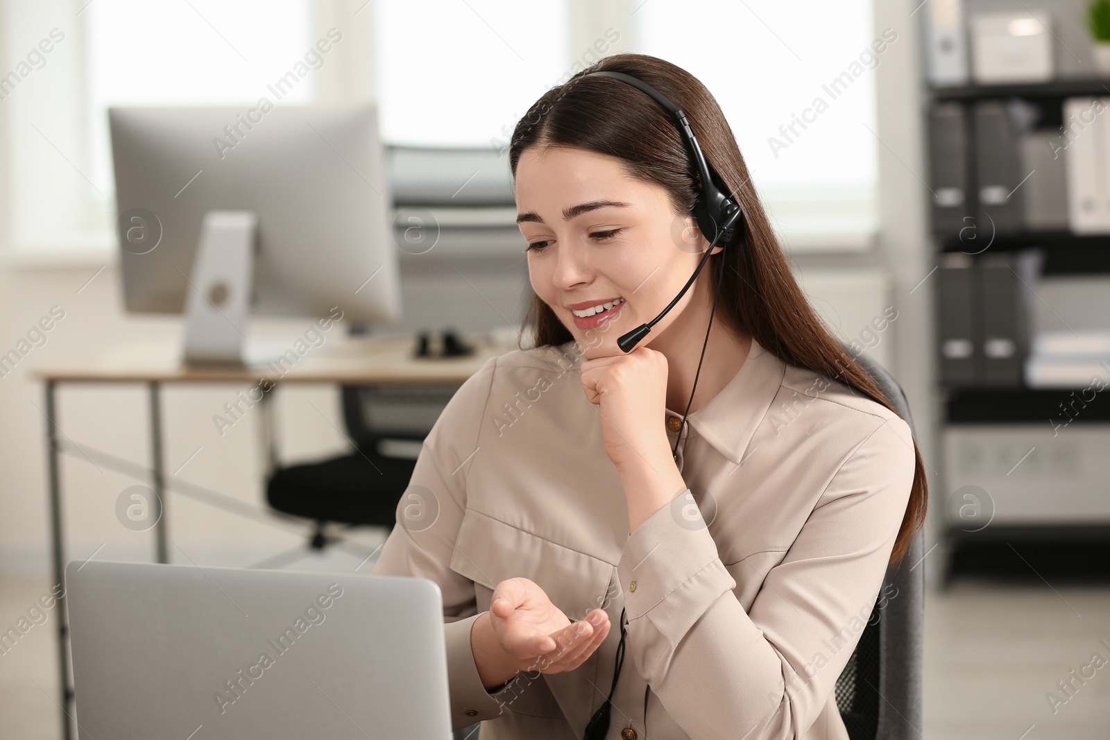 Photo of Hotline operator with headset working on laptop in office