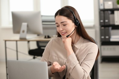 Hotline operator with headset working on laptop in office