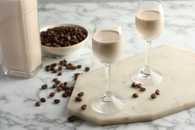 Coffee cream liqueur in glasses and beans on white marble table