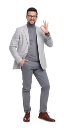 Handsome bearded businessman in eyeglasses showing OK gesture on white background