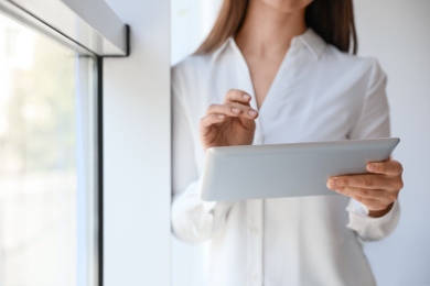 Photo of Businesswoman working with modern tablet in office, closeup