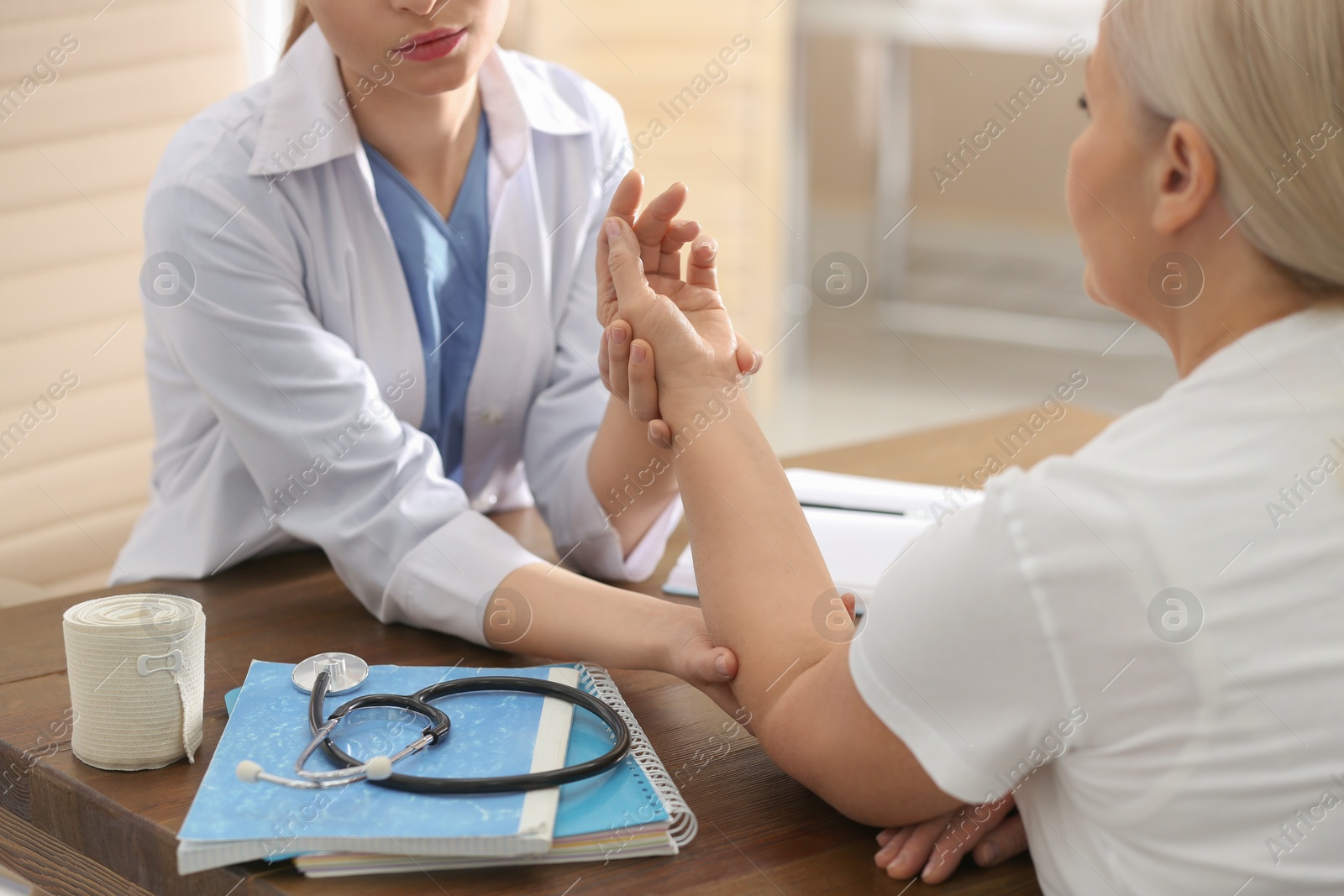 Photo of Female orthopedist examining patient with injured arm in clinic, closeup