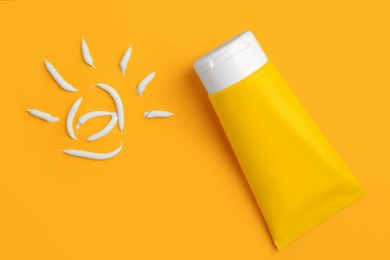 Photo of Drawing of sun and tube with sunscreen on orange background, top view. Skin protection