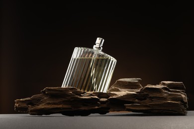 Photo of Luxury men`s perfume in bottle on grey table against dark background